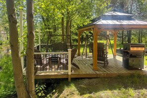Une terrasse en bois avec un belvédère, des sièges d’extérieur et un barbecue.