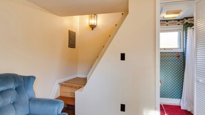 A staircase leading to a room with a blue chair, a light fixture, and a patterned wall. - Steps to Chautauqua Lake: Cozy Cottage w/ Gazebo (Mayville)