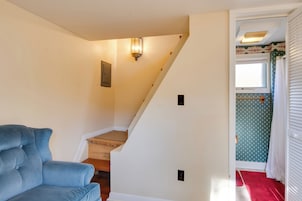 Una escalera conduce a una habitación con una silla azul, una lámpara y un papel tapiz decorado.