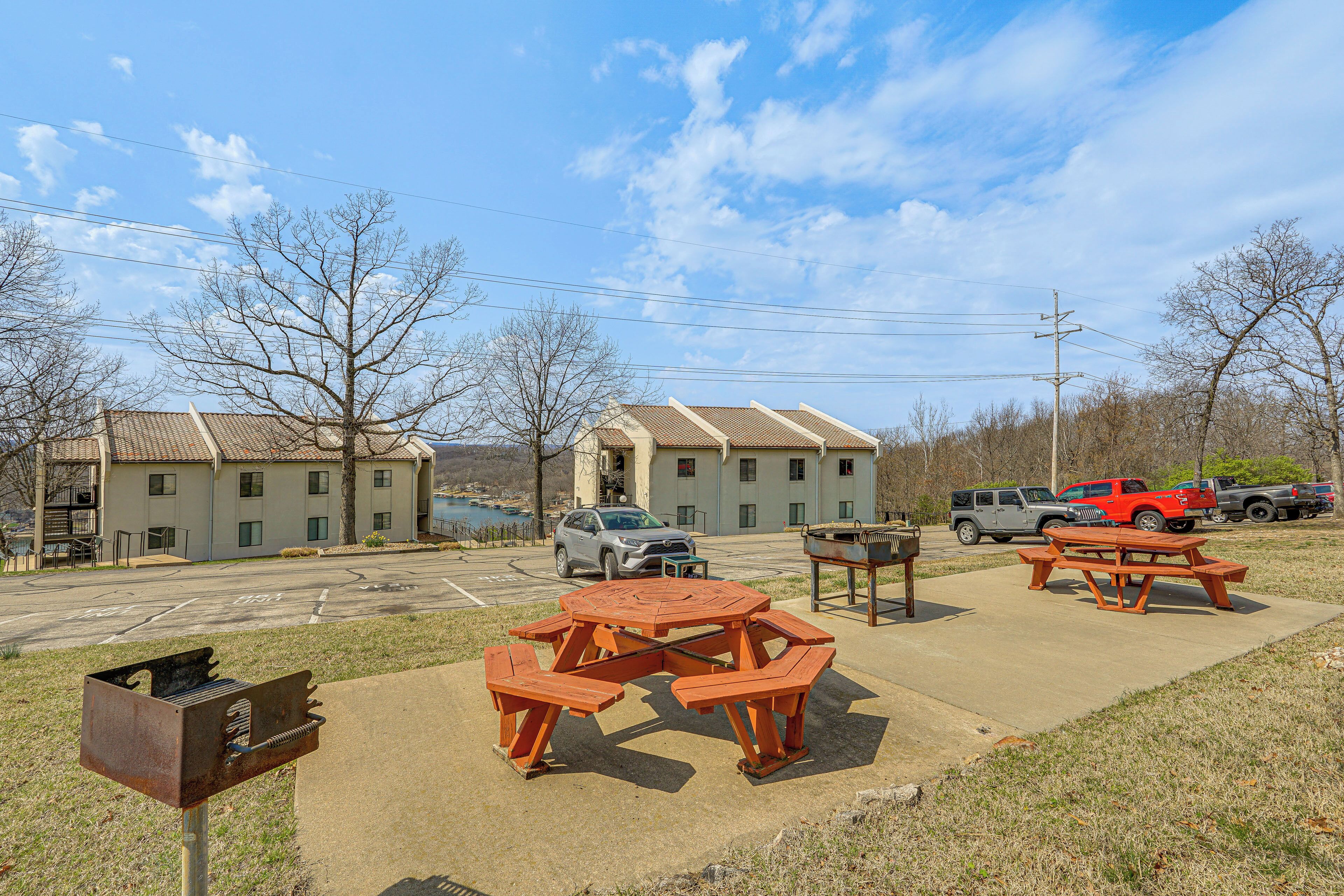 A picnic table and benches in a parking lot with buildings in the background.
