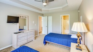 A bedroom with a bed, dresser, TV, ceiling fan, and lamp. - Lake Ozark Condo Rental w/ View & Pool Access! (Lake Ozark)