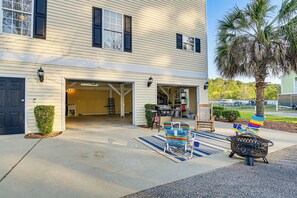 A two-story house with a garage, a covered patio area with outdoor furniture, and a palm tree.