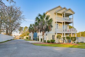 Stunning two-story residence with a spacious balcony and covered front porch, set amidst a beautifully manicured lawn and mature trees.