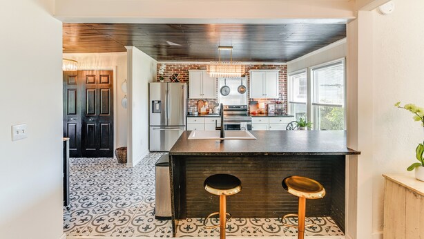 Een moderne keuken met een centraal eiland, roestvrijstalen apparatuur en een vloer met een patroon.