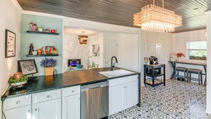 Een moderne keuken met een zwart aanrecht, witte kasten, een roestvrijstalen vaatwasser en een hangende lamp.