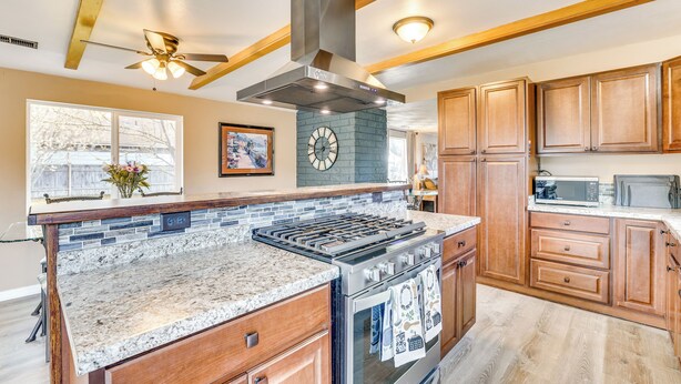 A kitchen with a central island, granite countertops, wooden cabinets, a stainless steel range hood, and a built-in oven. - Family-friendly Ontario Home in Central Location! (Ontario)