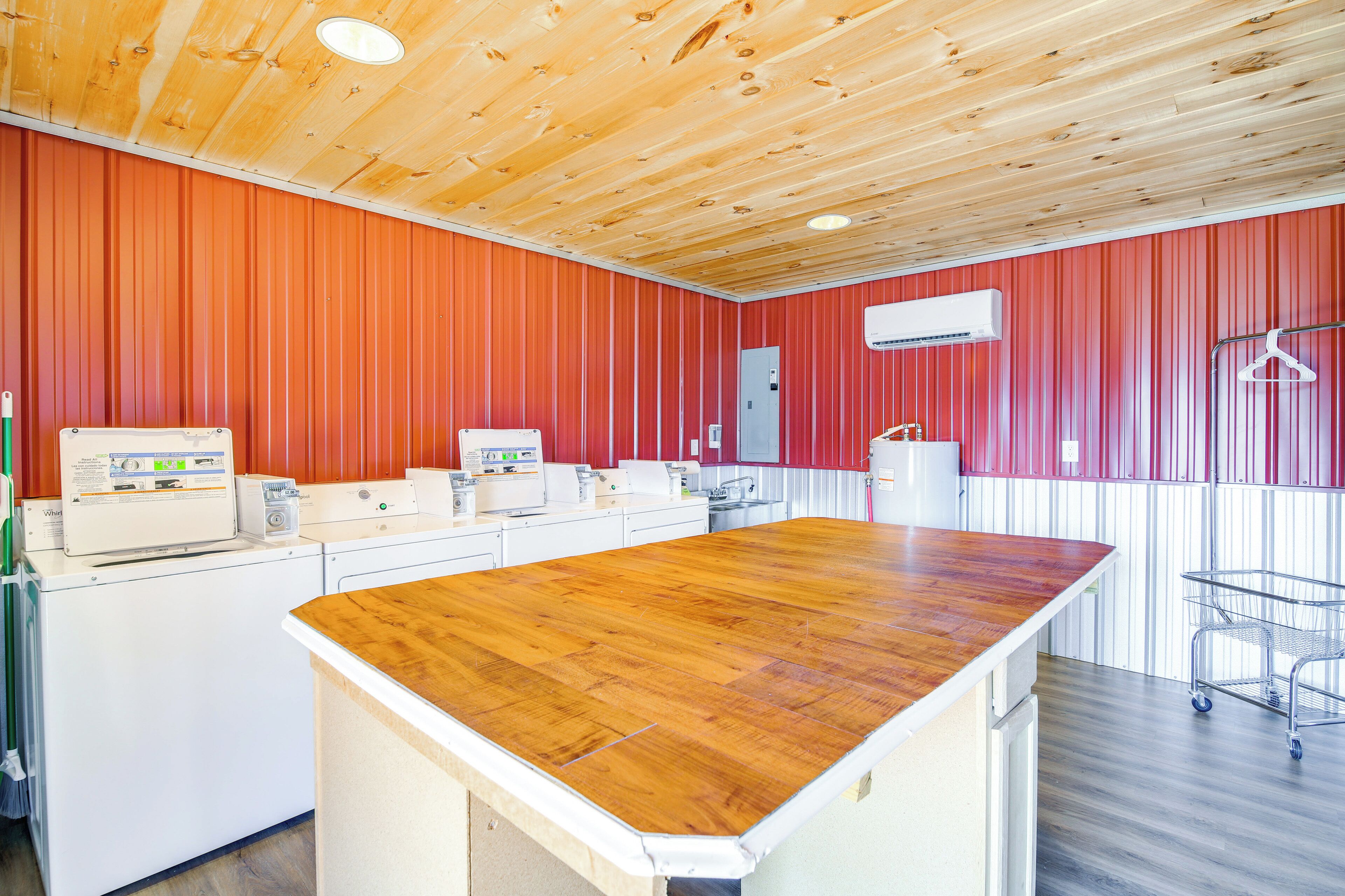 A kitchen with wooden ceiling, red wall panels, and a central island with a wooden countertop.