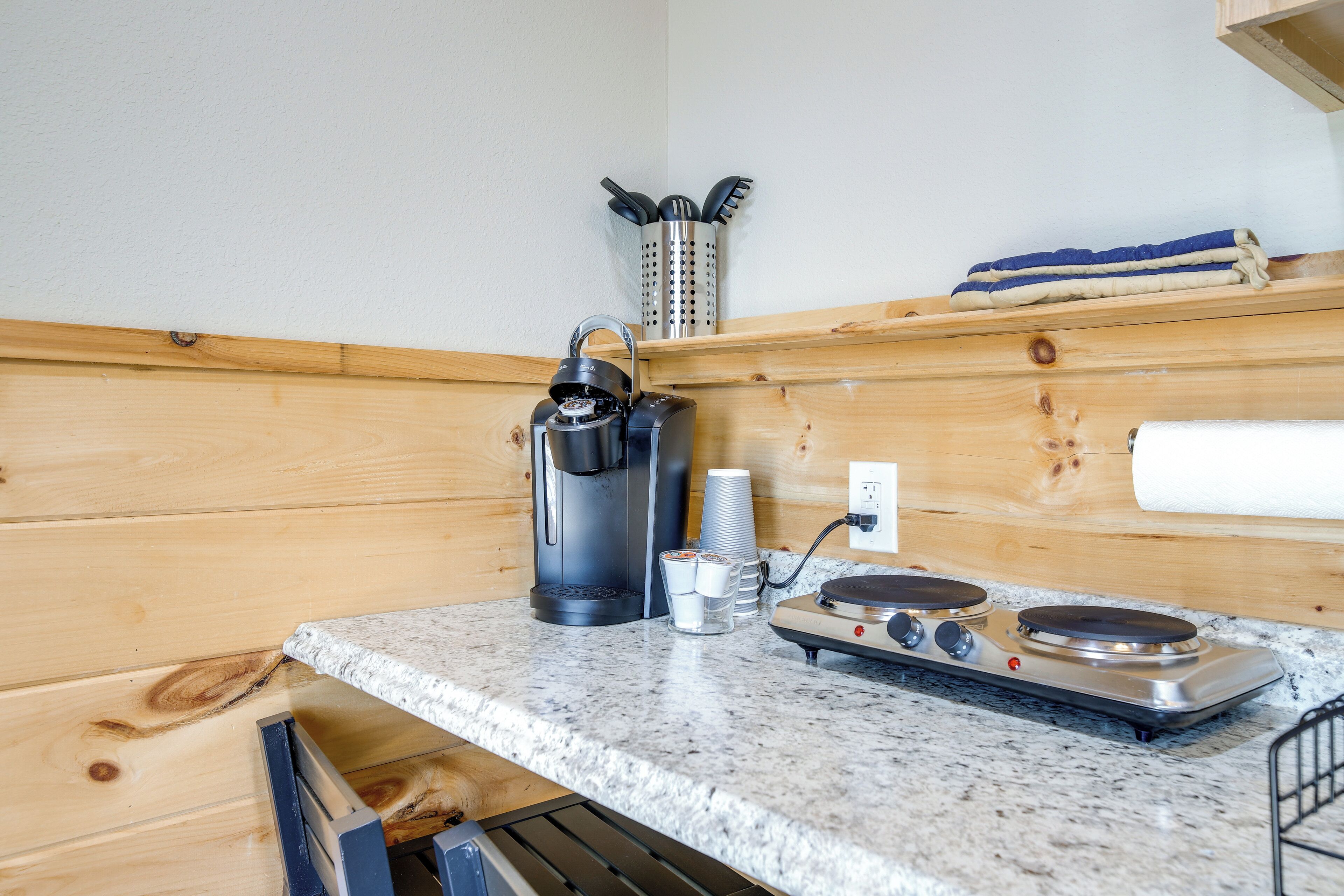 Una cocina con cafetera, estufa y un portalápices en la pared.