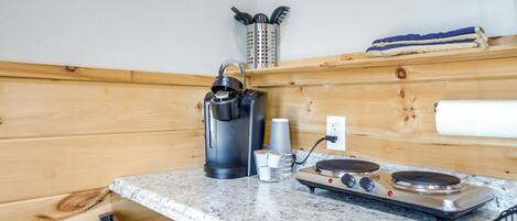 Una cocina con cafetera, estufa y un portalápices en la pared.
