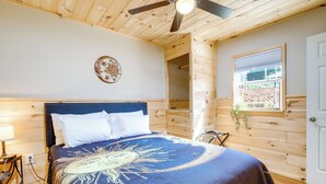 A bedroom with a bed, a ceiling fan, a window, and a wooden wall. - Near Hiking & Biking: Newport Cabin in the Smokies (Newport)