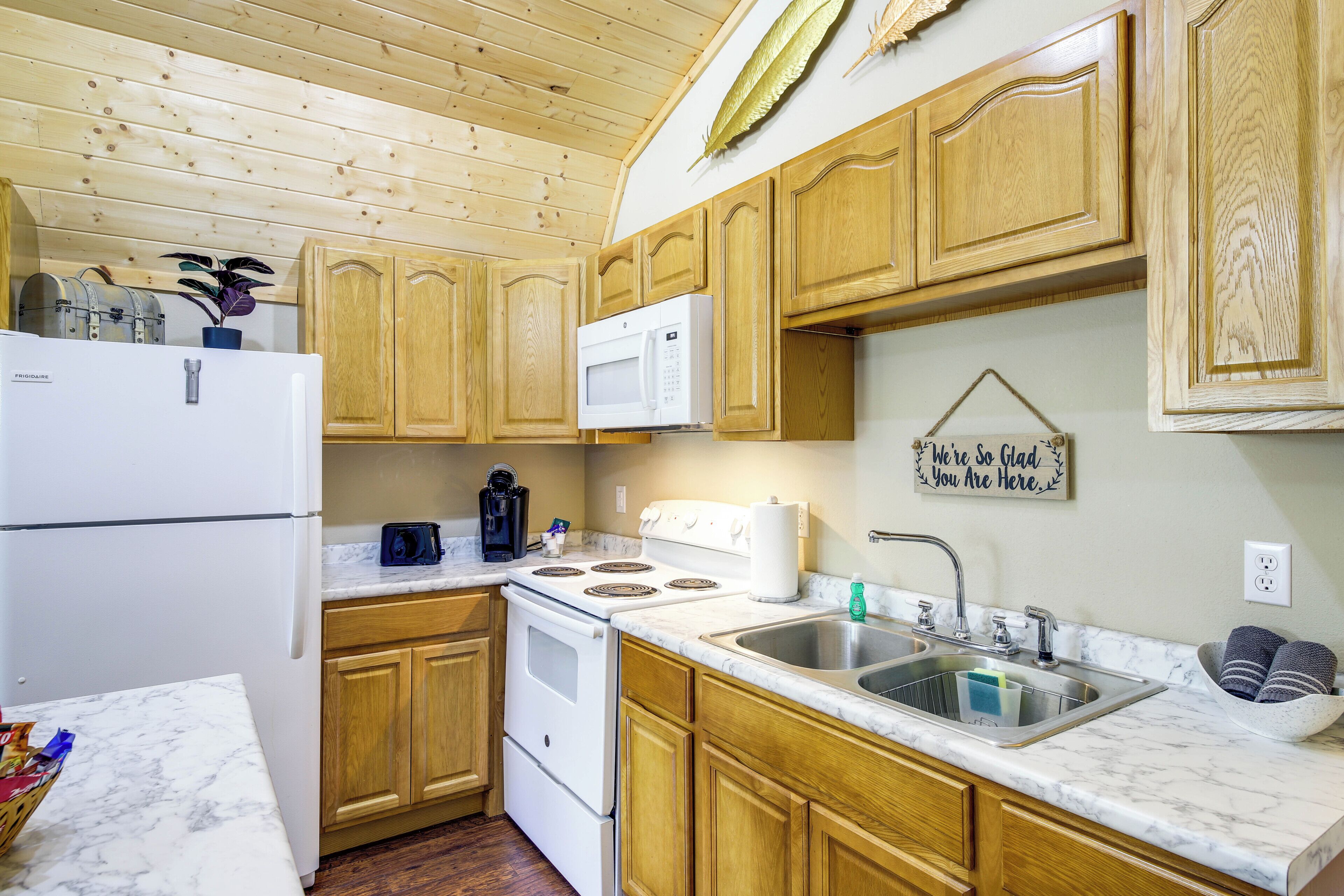 A kitchen with wooden cabinets, a white refrigerator, a microwave, a stove, and a sink.