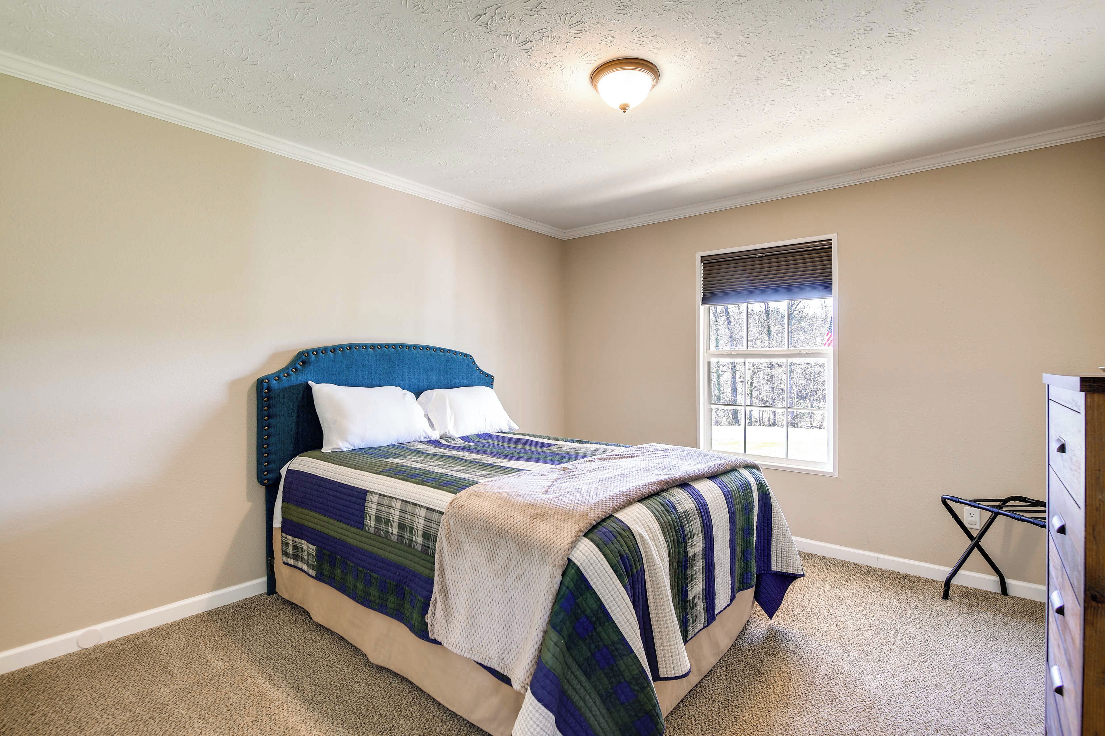 A bedroom with a bed, a window, and a dresser.