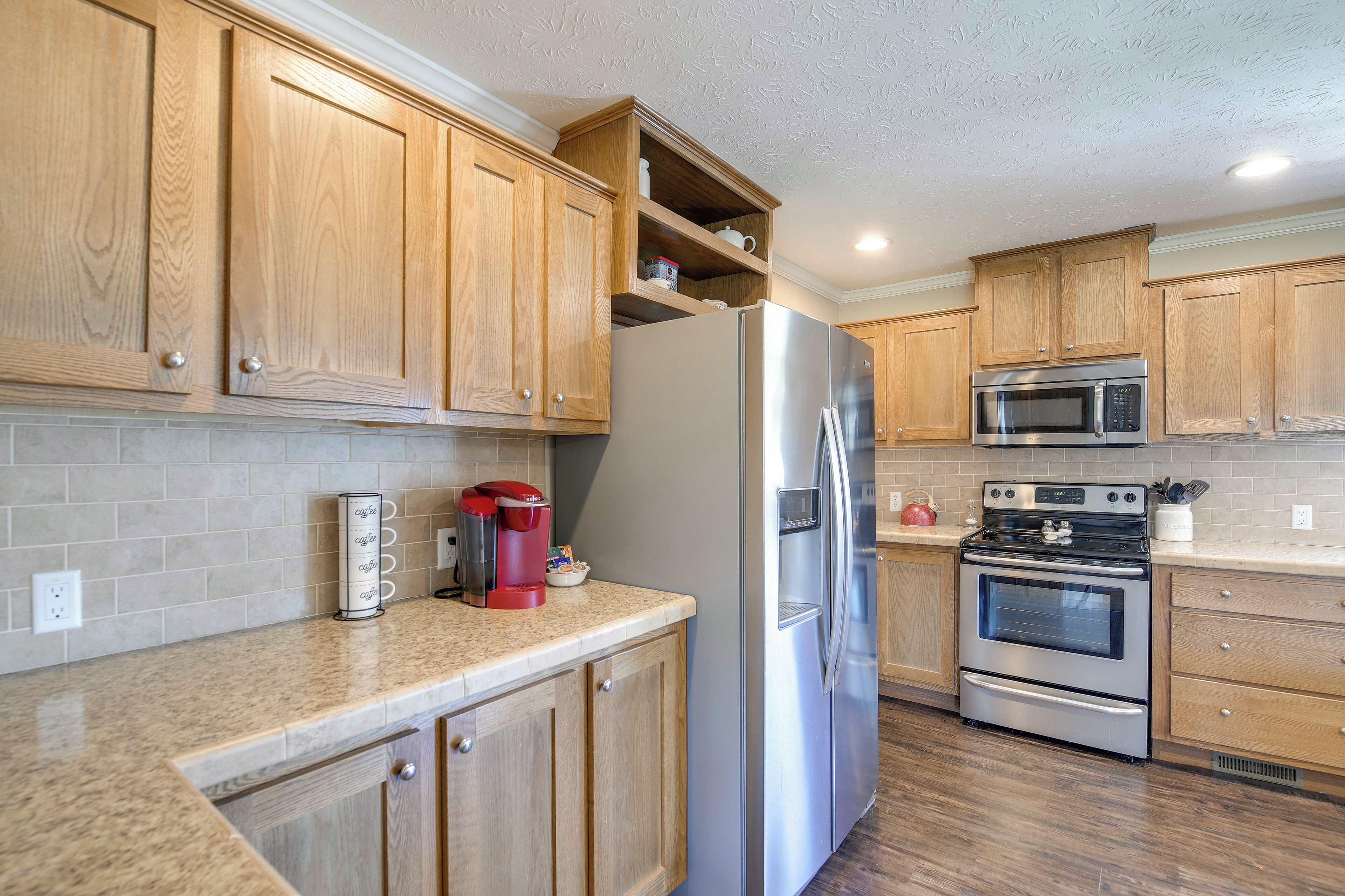 A kitchen with wooden cabinets, a stainless steel refrigerator, a microwave, and an oven.
