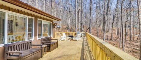 A wooden deck with outdoor furniture, overlooking a forested area.