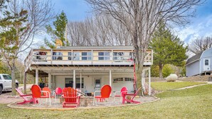 Une maison à deux étages avec un porche couvert, des chaises rouges et une table.