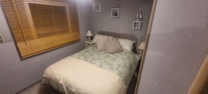 A small, cozy bedroom with a single bed, a bedside table with a lamp, and a window with blinds. - The Family Van - Withernsea Sands - Park Dean (Withernsea)