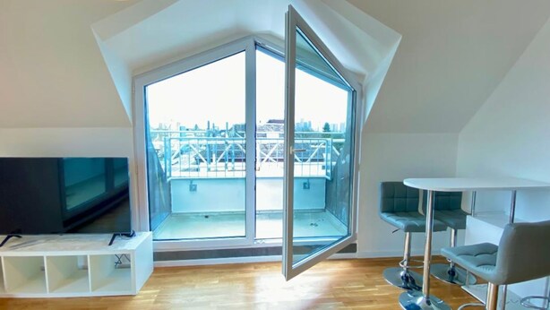 Eine moderne Wohnung mit einem großen Oberlicht, einem Flachbildfernseher und einer minimalistischen Möblierung.