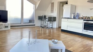 Eine moderne Küche mit weißen Schränken, einem Einbauofen und einem Essbereich mit einem weißen Tisch und Stühlen.