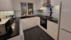 Una cucina moderna con mobili bianchi, un piano di lavoro nero, un fornello a gas e una finestra con vista.