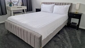 Una camera d'albergo ben ordinata con un letto grande, un comodino, una scrivania con una sedia e una finestra con tende.