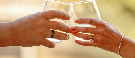 Two hands holding a clear glass, likely containing a beverage, against a blurred background with a wooden surface in the foreground.