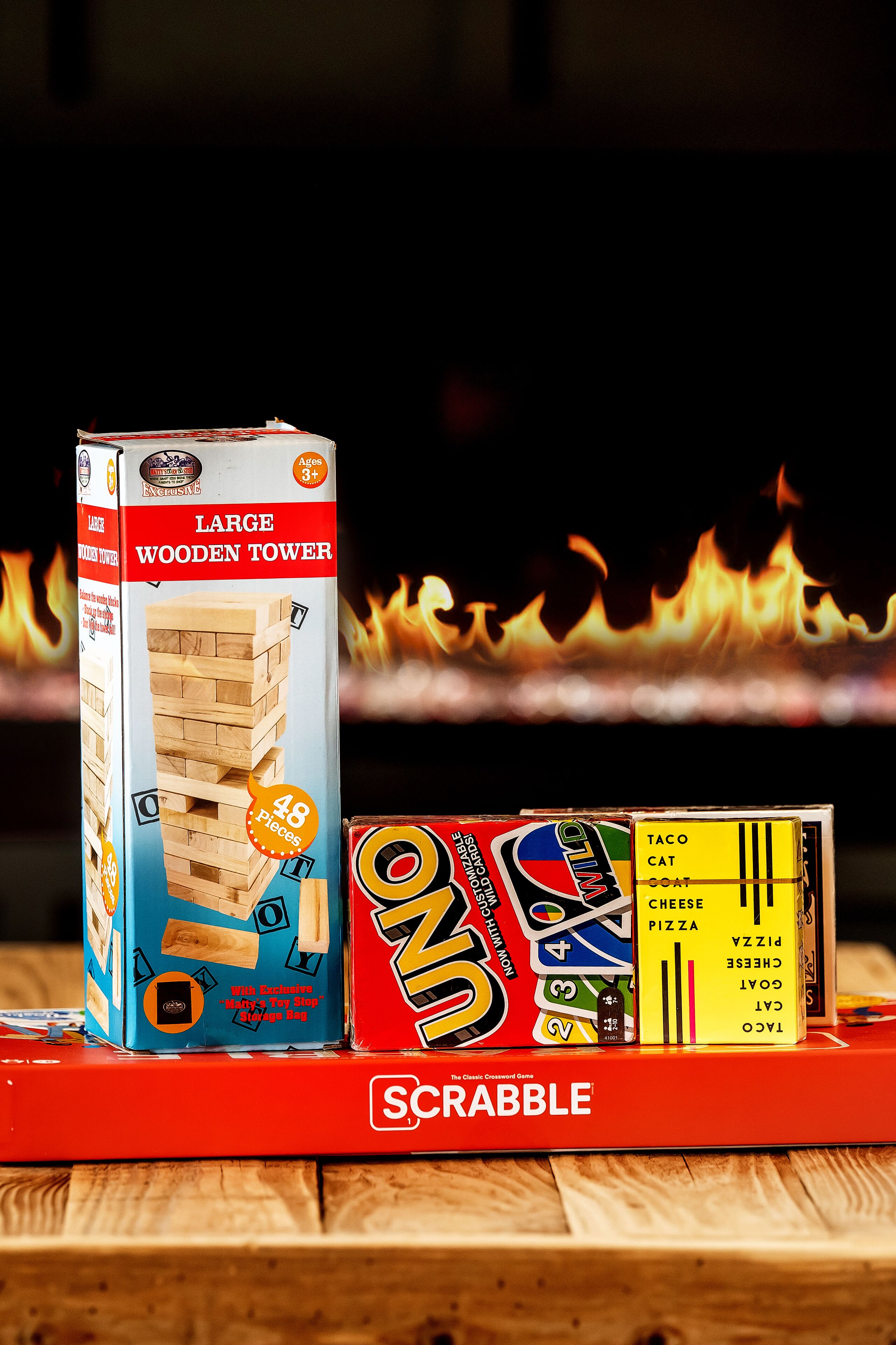 A Scrabble game set with a wooden tower and various letter tiles on a wooden surface.