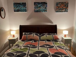 A bedroom with a bed, two bedside tables with lamps, and three framed artworks on the wall. - Beautifully Lit Airy 1-bed Apartment in Liverpool (Liverpool)