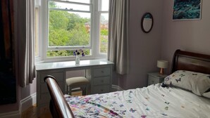 Ein Schlafzimmer mit einem Bett, einem Schreibtisch und einem Fenster mit Vorhängen.