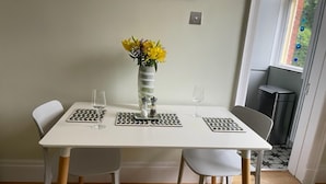 Ein Esstisch mit zwei Stühlen, einer Vase mit gelben Blumen und zwei Weingläsern.