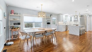 Una cocina moderna con una isla central, armarios blancos y un ventanal grande.