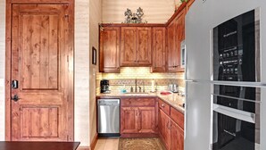 Eine Küche mit Holzausstattung, einem Edelstahl-Geschirrspüler und einem eingebauten Kühlschrank mit Digitalanzeige.