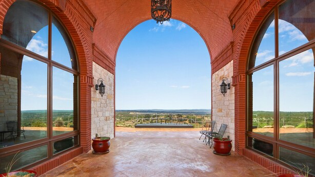 A covered patio with large windows offering a view of the landscape.