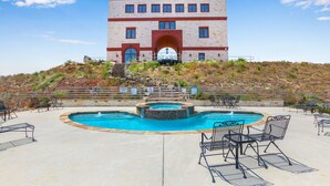 A hotel with a swimming pool, outdoor seating, and a staircase leading to the entrance.