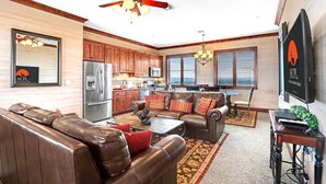 A spacious living area with leather sofas, a dining table, and a kitchen in the background.