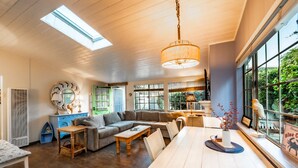 Un salon spacieux avec un grand canapé, une table à manger et une vue sur la verdure environnante.