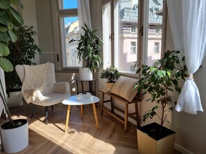 Ein gemütliches Wohnzimmer mit einer Couch, einem kleinen runden Tisch und Zimmerpflanzen.