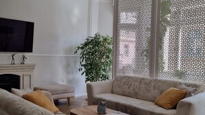 A modern living room with a beige sofa, a coffee table, and a large window with decorative screens. - King Paul Suites Down Town Budapest in the heart of the city (Budapest, V. kerület)