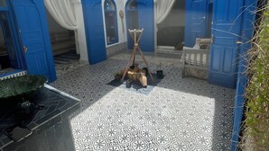 A courtyard with blue doors, white curtains, and patterned floor tiles. - DarBaali Inn (Rabat)