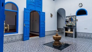 A room with blue doors, a tiled floor, and a small fountain. - DarBaali Inn (Rabat)
