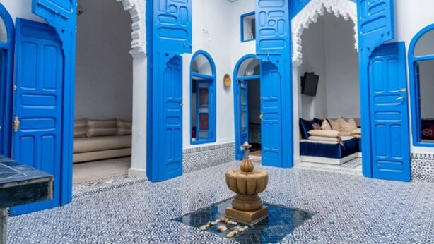 A room with blue doors and white walls, a patterned floor, and a bed with pillows. - DarBaali Inn (Rabat)