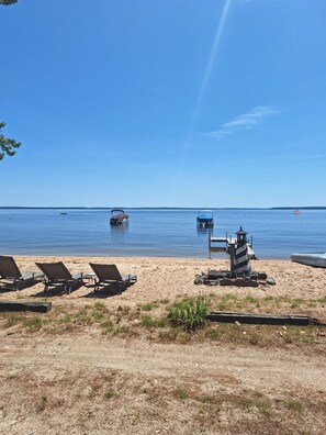 Uma praia com cadeiras de praia, uma torre de salva-vidas e barcos na água.