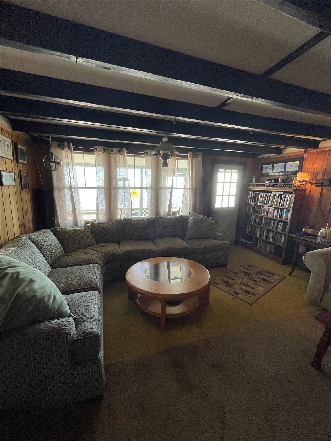 A cozy living room with a sectional sofa, a round coffee table, and a bookshelf.