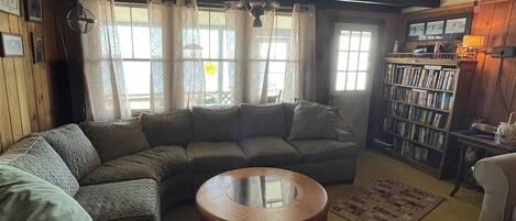 A cozy living room with a sectional sofa, a round coffee table, and a bookshelf.