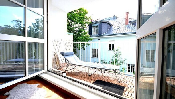 A modern room with large windows, a wooden deck, and a white chair. - Vienna Residence, Steckhovengasse - Hietzing #4888 (Vienna)