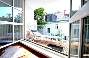 A modern room with large windows, a wooden deck, and a white chair. - Vienna Residence, Steckhovengasse - Hietzing #4888 (Vienna)