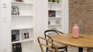 A dining area with a brick wall, white shelving units, and a wooden table with chairs. - Vienna Residence, Wasagasse - Alsergrund #6294 (Vienna)