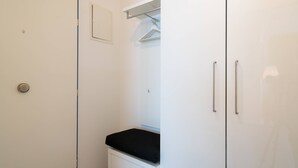 Ett badrum med en vit dörr, en svart handduk på en vit bänk och en spegel ovanför ett vitt skåp med två handtag.