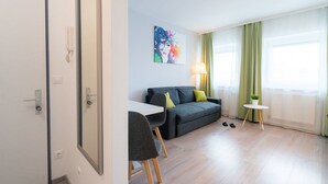 Una sala de estar moderna con un sofá gris, una mesita con una planta y un cuadro en la pared.