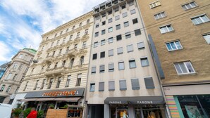 Un edificio de varios pisos con una mezcla de estilos arquitectónicos, que incluye una fachada clásica y una sección moderna con amplios ventanales.