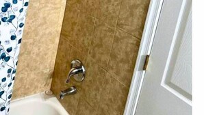 A bathroom with a bathtub, a shower, and a toilet. - Room G Divine Villa and Resorts (Newark)